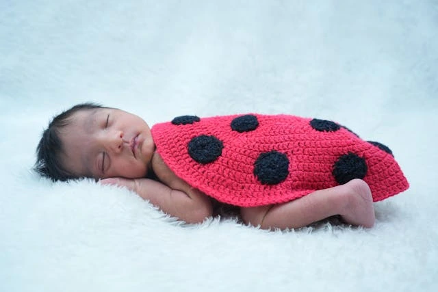 un bébé avec une couverture qui imite la coccinelle